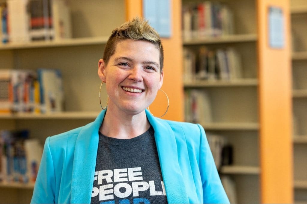 A person smiles at camera in a library.